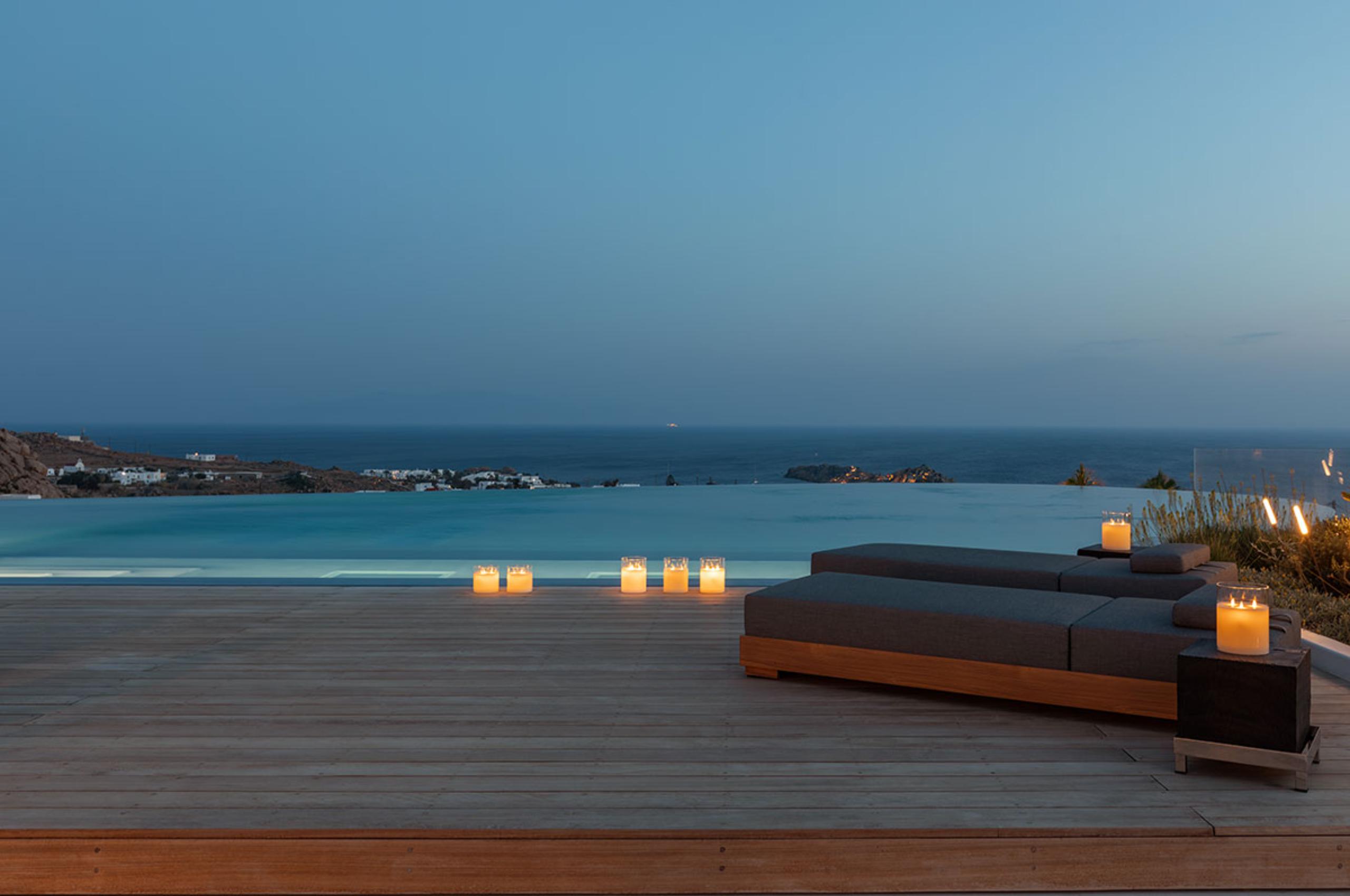villa-petra-terrace-infinity-swimming-pool-night-candelit-sunbeds-scenic-sea-views-luxury-mykonos